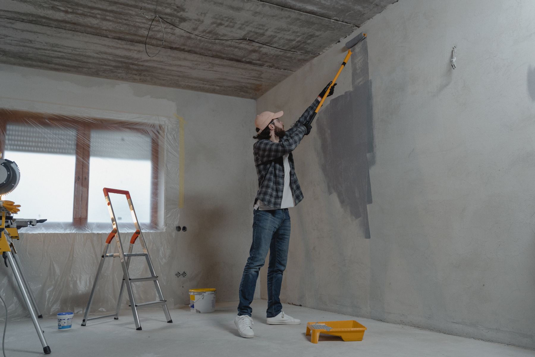 Painter cutting in a ceiling with a roller on an extension pole